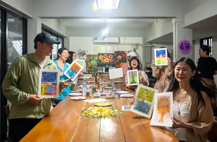 人们在长桌旁交流并展示彩色作品