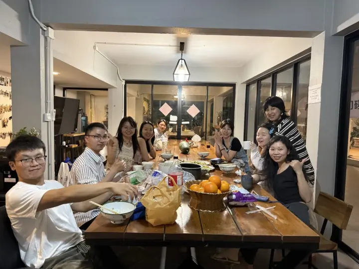 人们围坐餐桌用餐并看向镜头