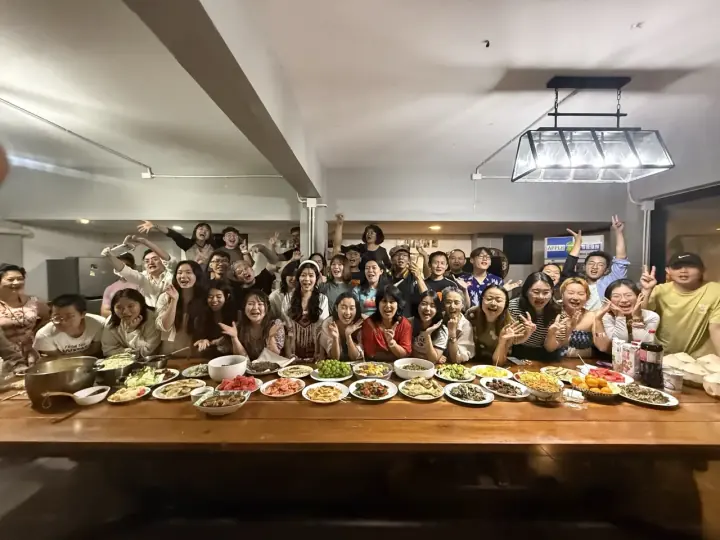一大群人围坐在长桌旁聚餐合影